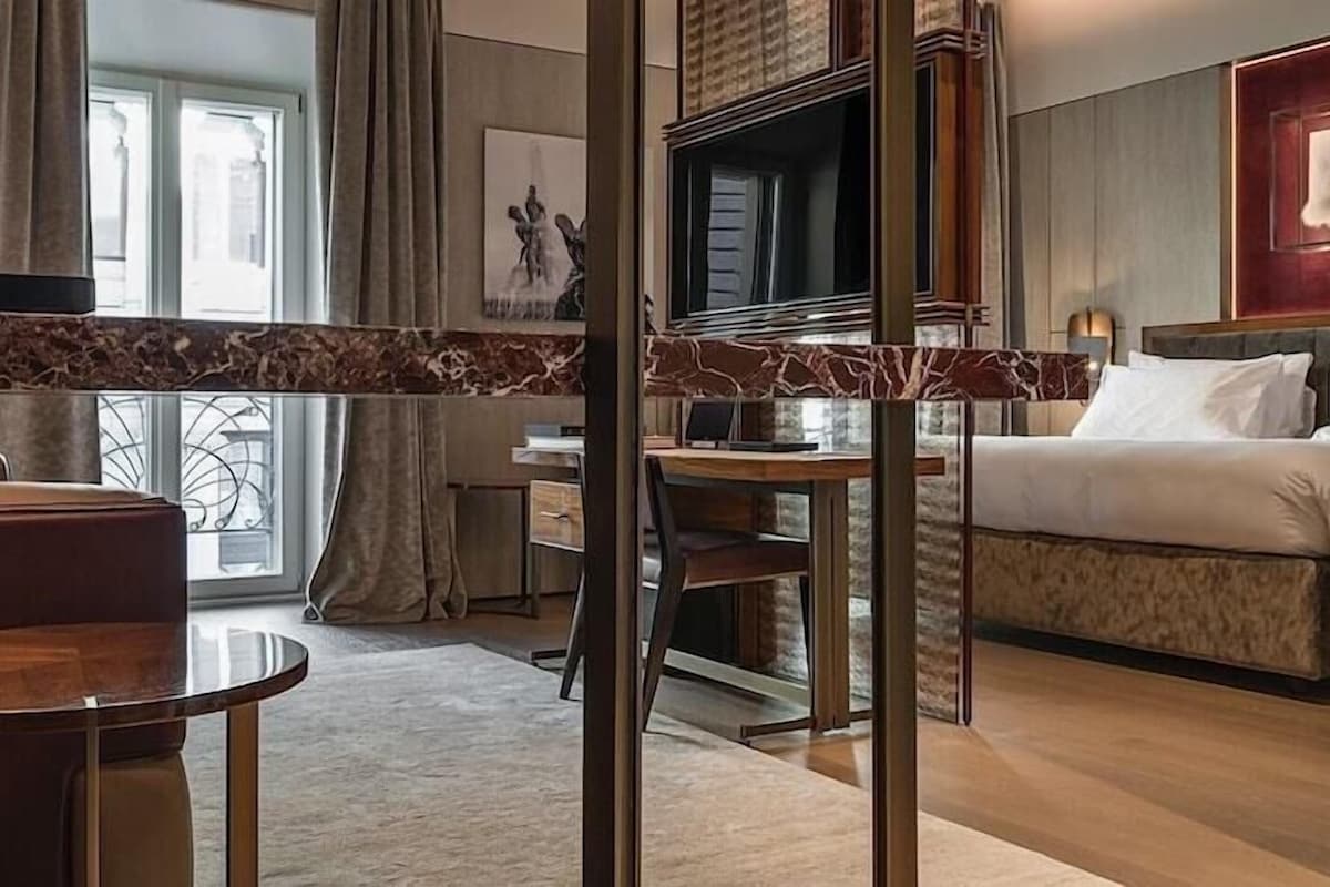 A hotel room with a bed, a sofa, a desk, and a TV.