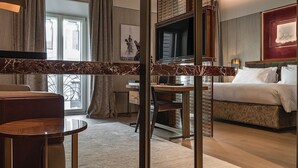 A modern hotel room with a bed, a sofa, a desk, and a TV. - Fendi Private Suites (Rome)