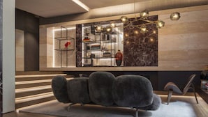 A modern interior with a sofa, a marble wall, and a shelf with decorative items. - Fendi Private Suites (Rome)