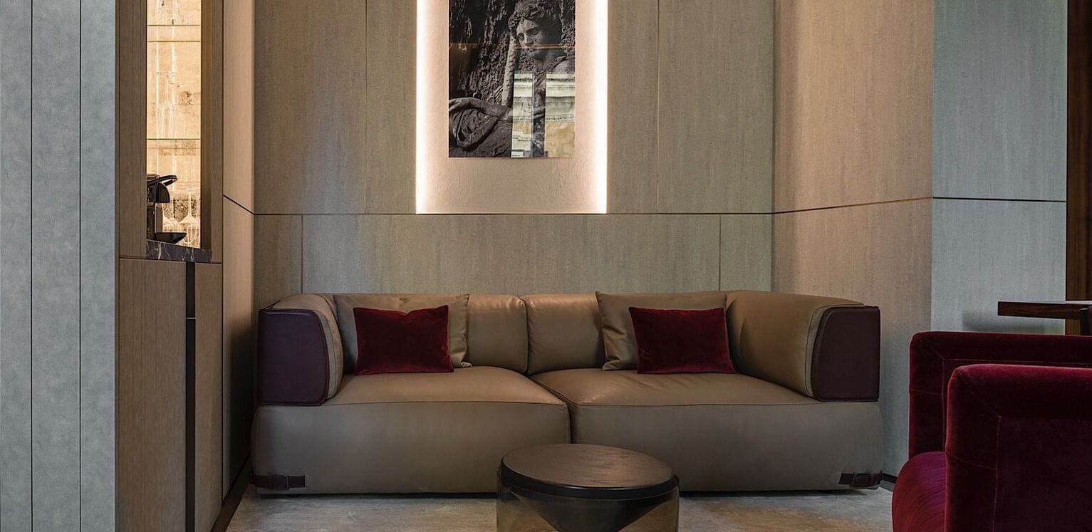 A modern living room with a beige sofa, a small round table, and a red chair.
