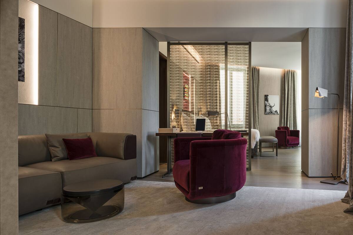 A modern living room with a sofa, a red chair, a coffee table, and a desk with a computer.