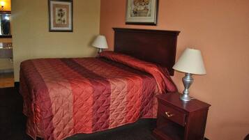 A hotel room with a large bed, two bedside lamps, a nightstand, and two framed pictures on the wall.