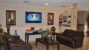 Un salón con un sofá de cuero marrón, una mesa de centro y un televisor montado en la pared.