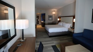 Ein Hotelzimmer mit Bett, Schreibtisch, Stuhl, Fernseher, Lampe und einer Couch.