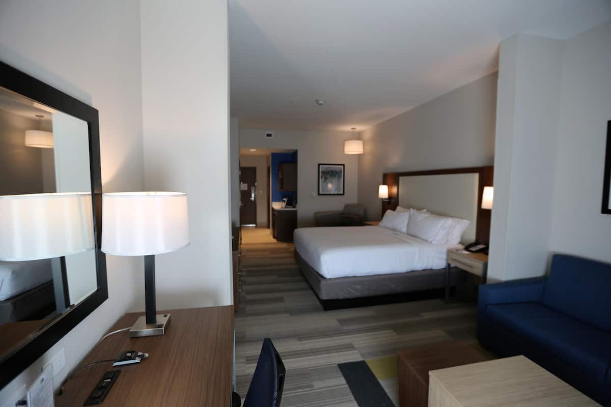 Een hotelkamer met een bed, een bureau, een stoel, een televisie, een lamp en een bank.