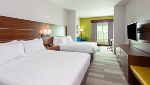 Ein Hotelzimmer mit zwei Betten, einem Schreibtisch, einem Sessel, einem Fernseher und einem Fenster mit Vorhängen.