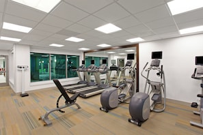 Un gimnasio con cintas de correr, elípticas y bicicletas estáticas.