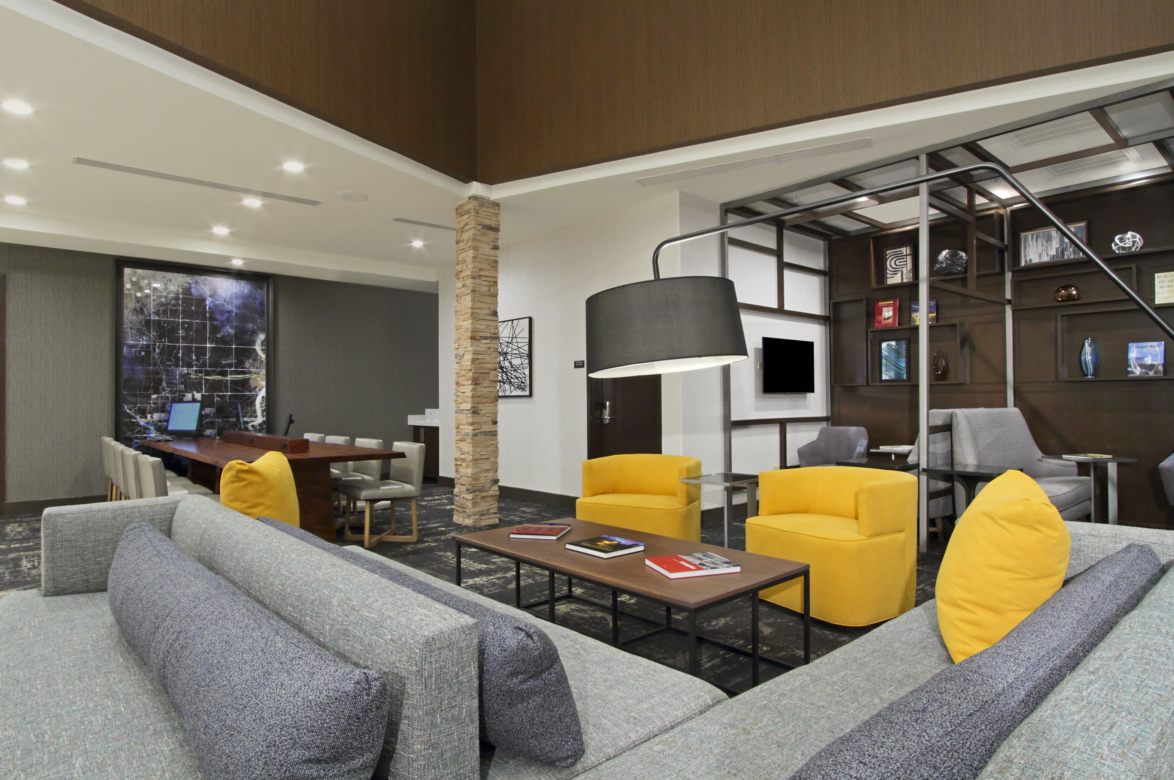 A modern hotel lobby with a seating area, a reception desk, and a staircase.