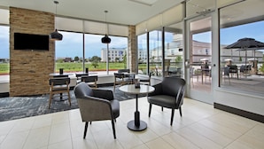 Un espace de détente intérieur moderne, avec des murs en pierre, de grandes fenêtres et un téléviseur à écran plat.