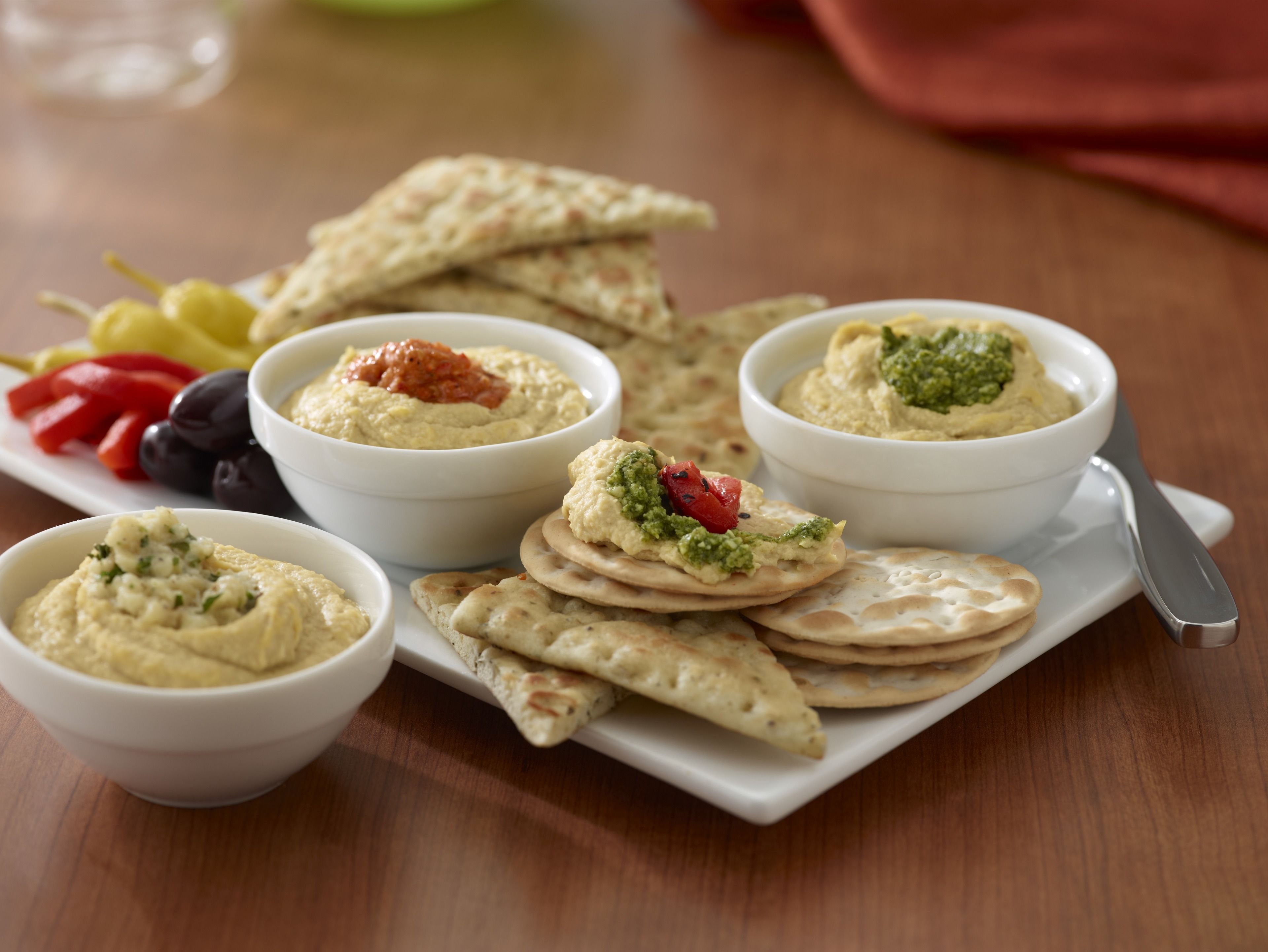 Une assiette de houmous garnie de divers accompagnements, du pain pita et des légumes.