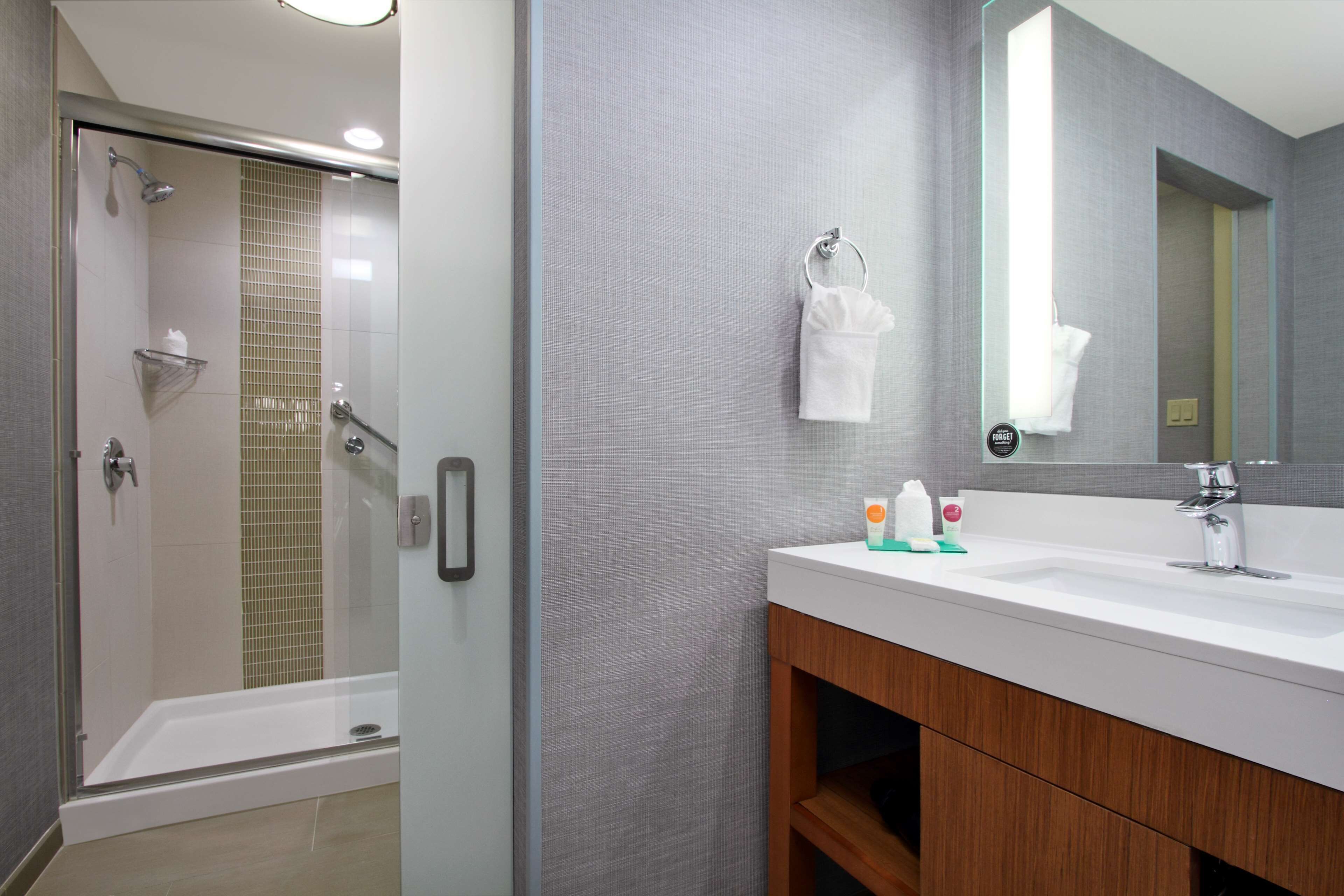 A modern bathroom with a glass-enclosed shower, a white sink, and a large mirror.