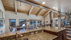 A spacious kitchen with granite countertops, a stainless steel sink, and a stone fireplace. - Snowmass Mountain Condos by Snowmass Vacations (Snowmass Village)