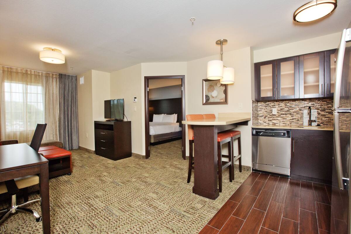 Habitación de hotel con comedor, kitchenette y una cama.