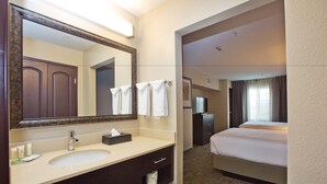 Casa de banho de hotel com lavatório, espelho e porta-toalhas.