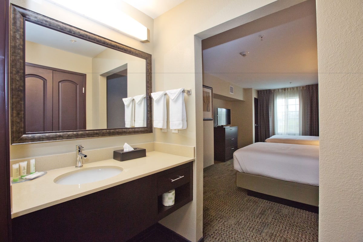 Un baño de hotel con lavamanos, espejo y toallero.