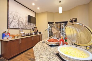 A buffet setup with various food items and a large metal bowl. - Staybridge Suites Austin South Interstate Hwy 35 by IHG (Austin)