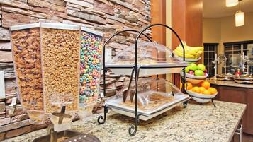 A buffet setup with cereal, fruit, and a coffee station.