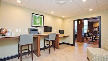 A hotel room with a desk, two chairs, a globe, a printer, and a framed picture on the wall.