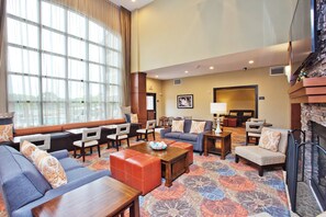 A hotel lobby with a seating area, a fireplace, and a large window. - Staybridge Suites Austin South Interstate Hwy 35 by IHG (Austin)