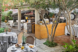 An outdoor café with tables and chairs, a wooden counter, and a stone wall. - Angelo d'Oro Heritage Hotel (Rovinj)