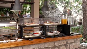 A buffet setup with various food items and a juice dispenser.