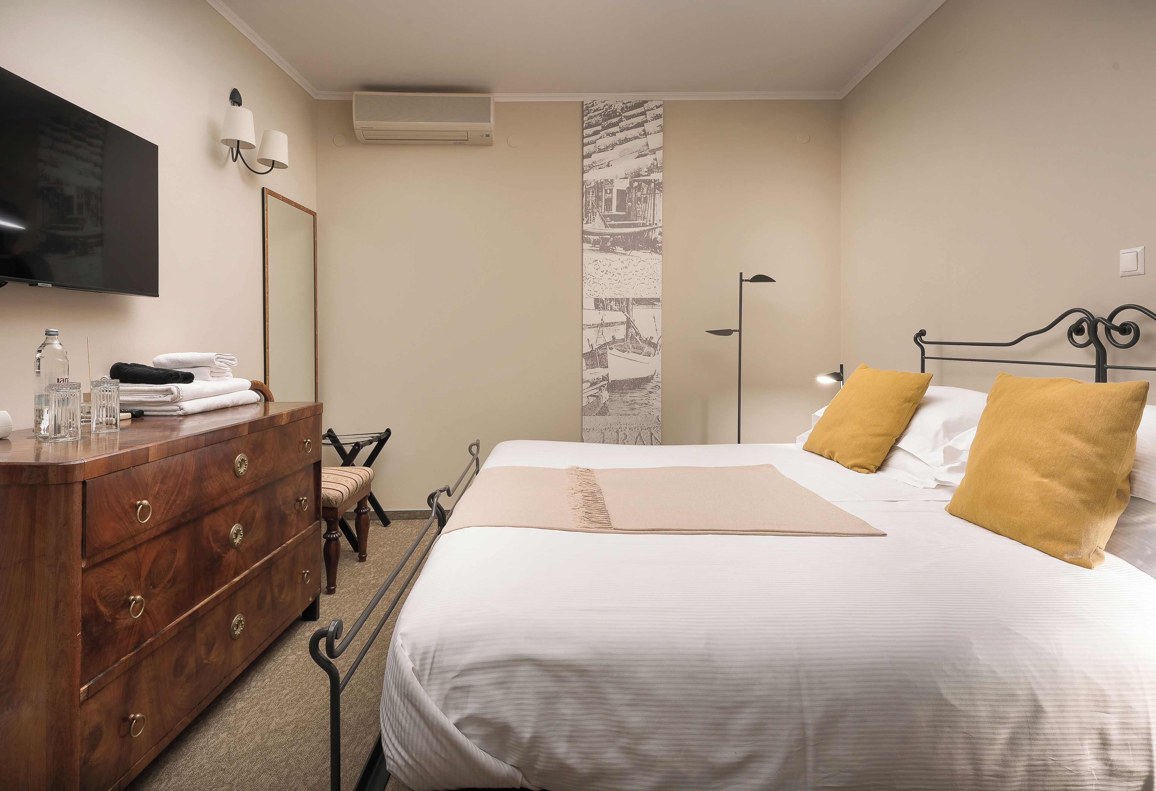 A hotel room with a bed, a wooden dresser, a television, and a mirror.