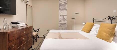 A hotel room with a bed, a wooden dresser, a television, and a mirror.