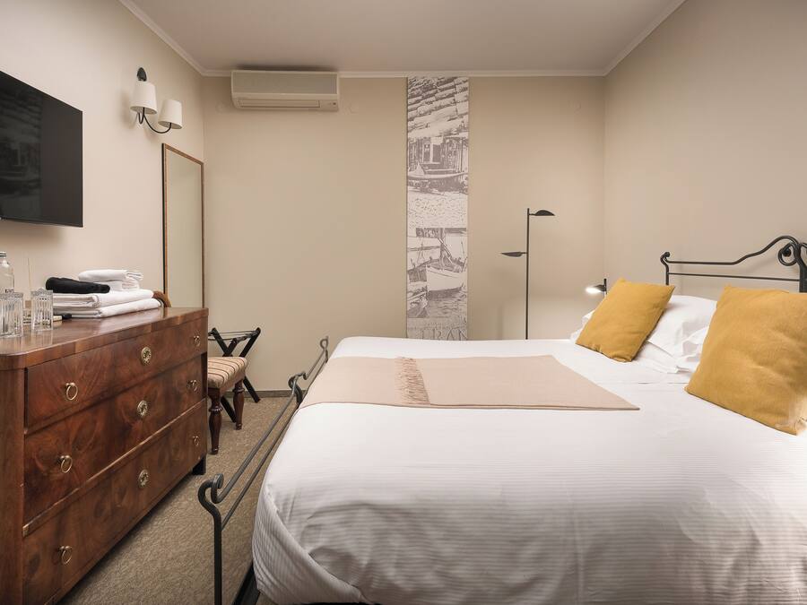 A hotel room with a bed, a wooden dresser, a television, and a mirror.