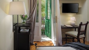 Een hotelkamer met een bed, een bureau met stoel, een televisie, een lamp en een raam met gordijnen.