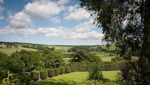 A lush green landscape with rolling hills, a well-maintained hedge, and a clear blue sky. - The Fell Hotel (Skipton)