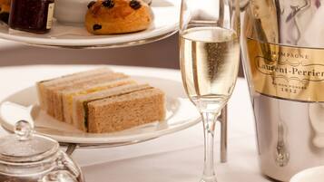 A table setting with sandwiches, a glass of champagne, and a bottle of Laurent-Perrier champagne.