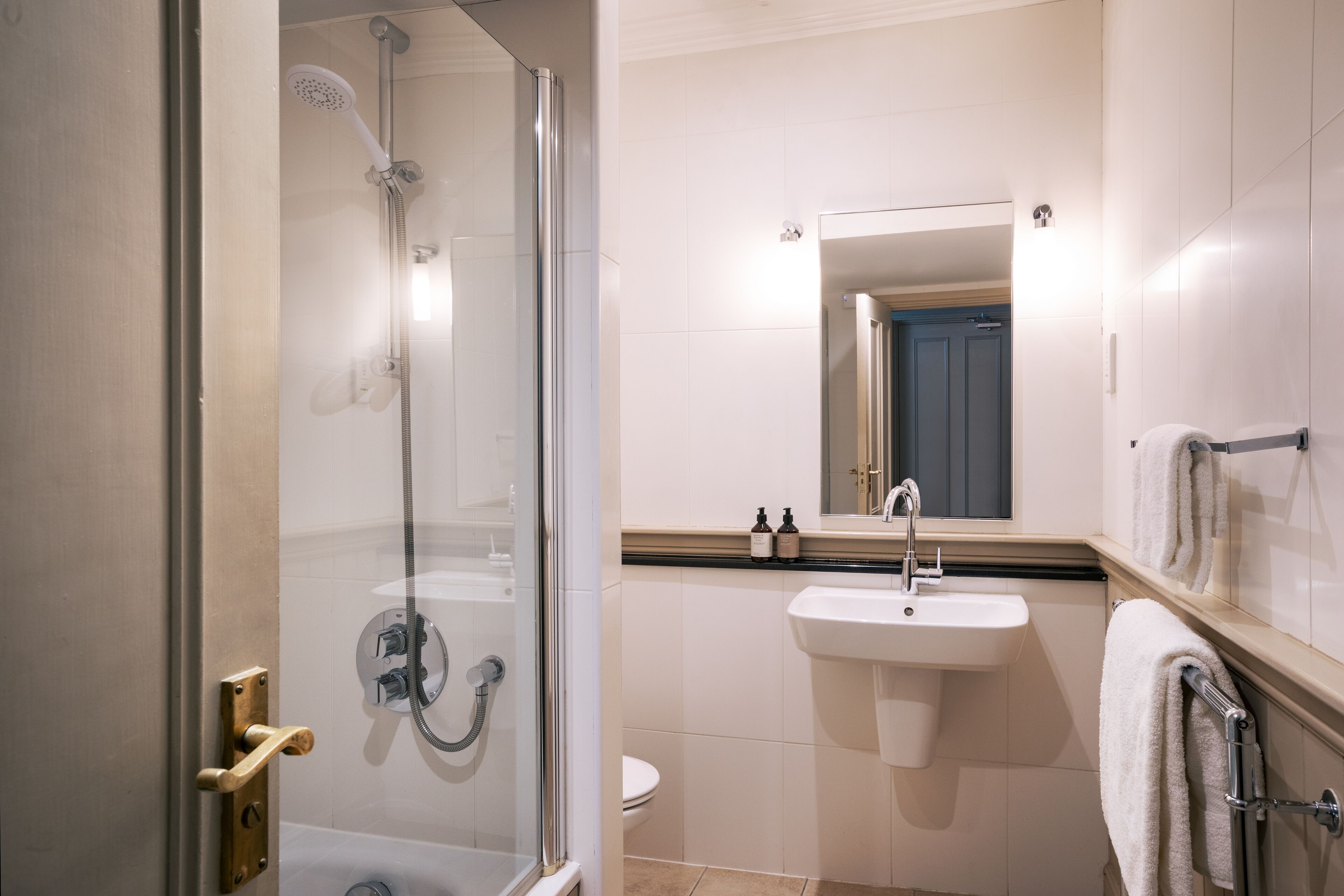 A modern bathroom with a glass-enclosed shower, a sink, and a mirror.