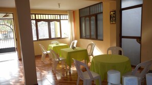Un espace repas avec des tables et des chaises, un ventilateur de plafond et une vue par la fenêtre.