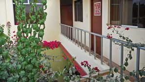 Un bâtiment avec un toit rouge, une enseigne portant l’inscription « HS » sur la porte et un balcon doté d’une rambarde en métal.