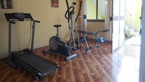 Une salle de sport à domicile équipée d’un tapis de course, d’un vélo d’appartement et d’un banc de musculation.
