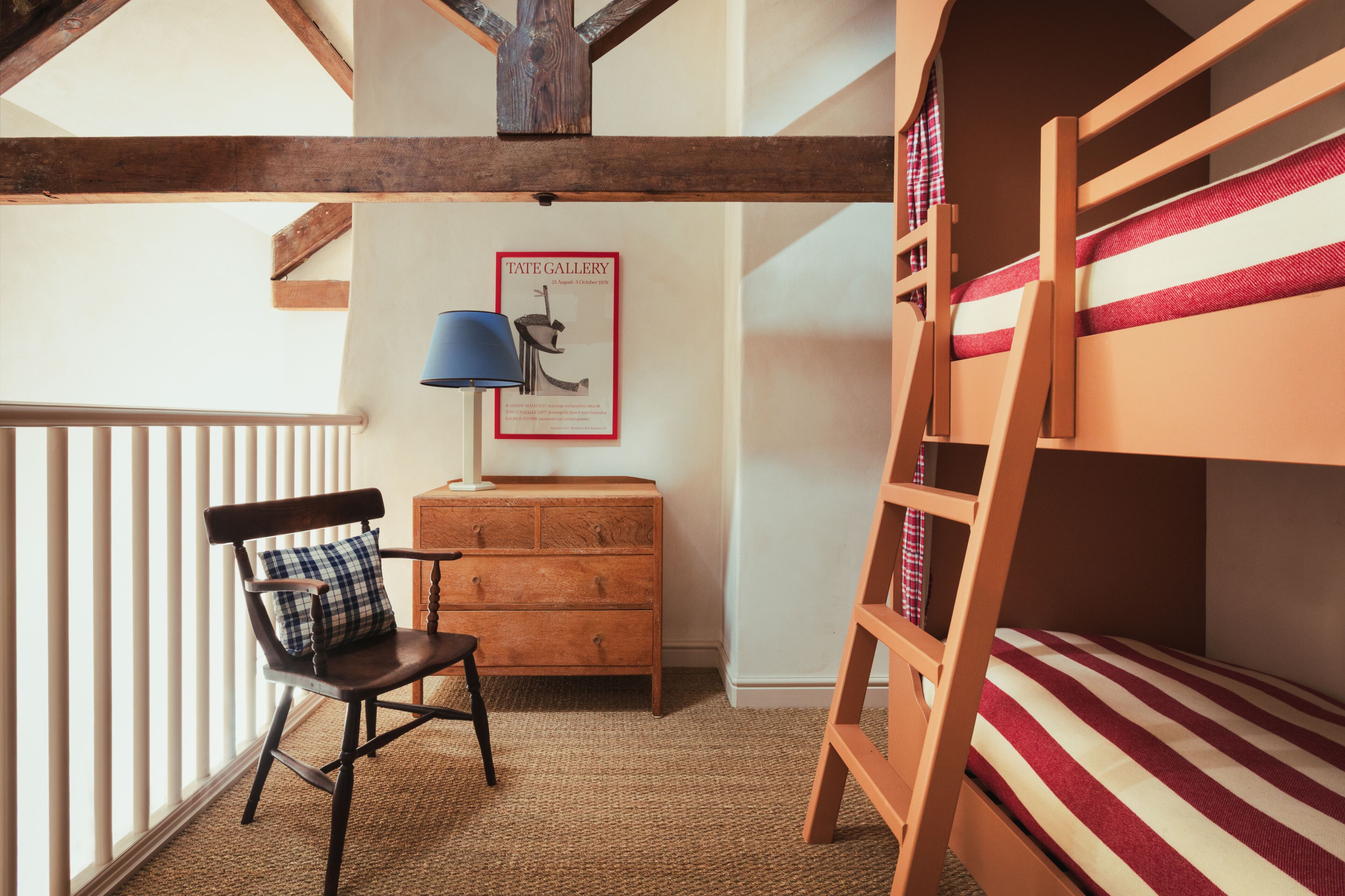 A room with a bunk bed, a wooden dresser, a chair, and a lamp.