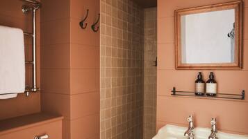 A bathroom with a toilet, sink, mirror, shower, and towel rack.