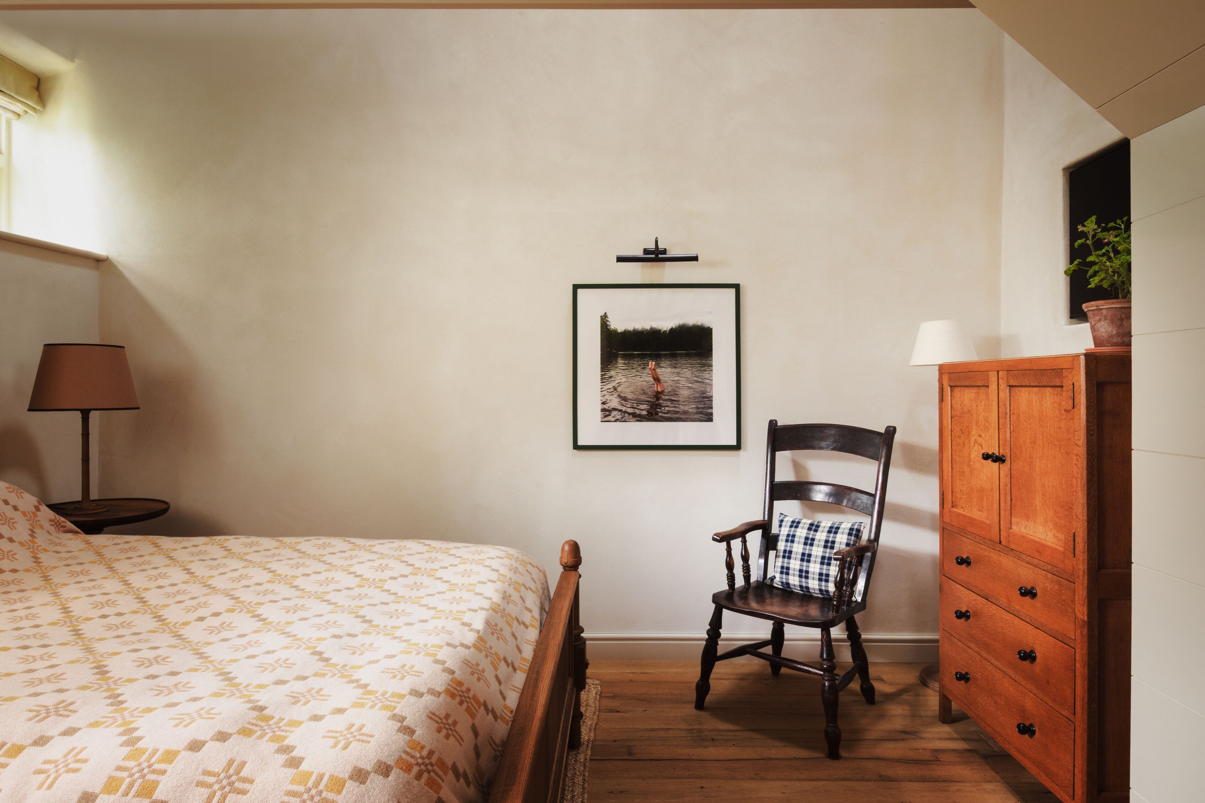 A bedroom with a bed, a chair, a dresser, and a framed picture on the wall.