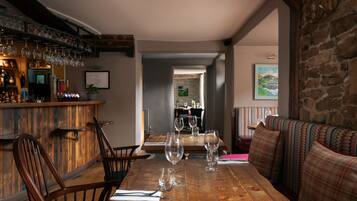 Uma mesa de jantar de madeira com cadeiras, um espaço de bar com copos e vista para a sala de jantar.