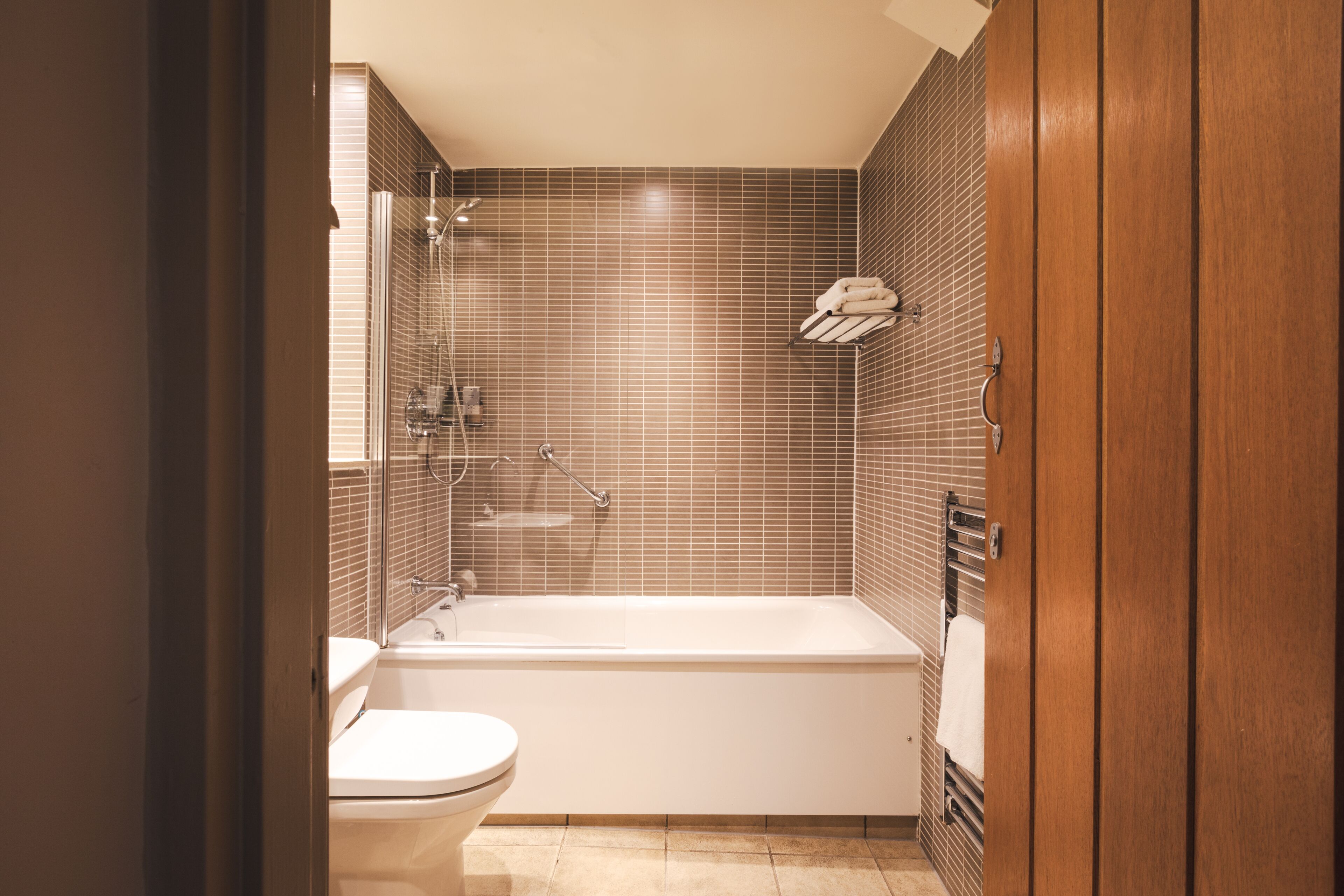 Een moderne badkamer met een bad, toilet en douche met glazen wanden.