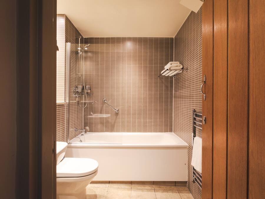 Een moderne badkamer met een bad, toilet en douche met glazen wanden.