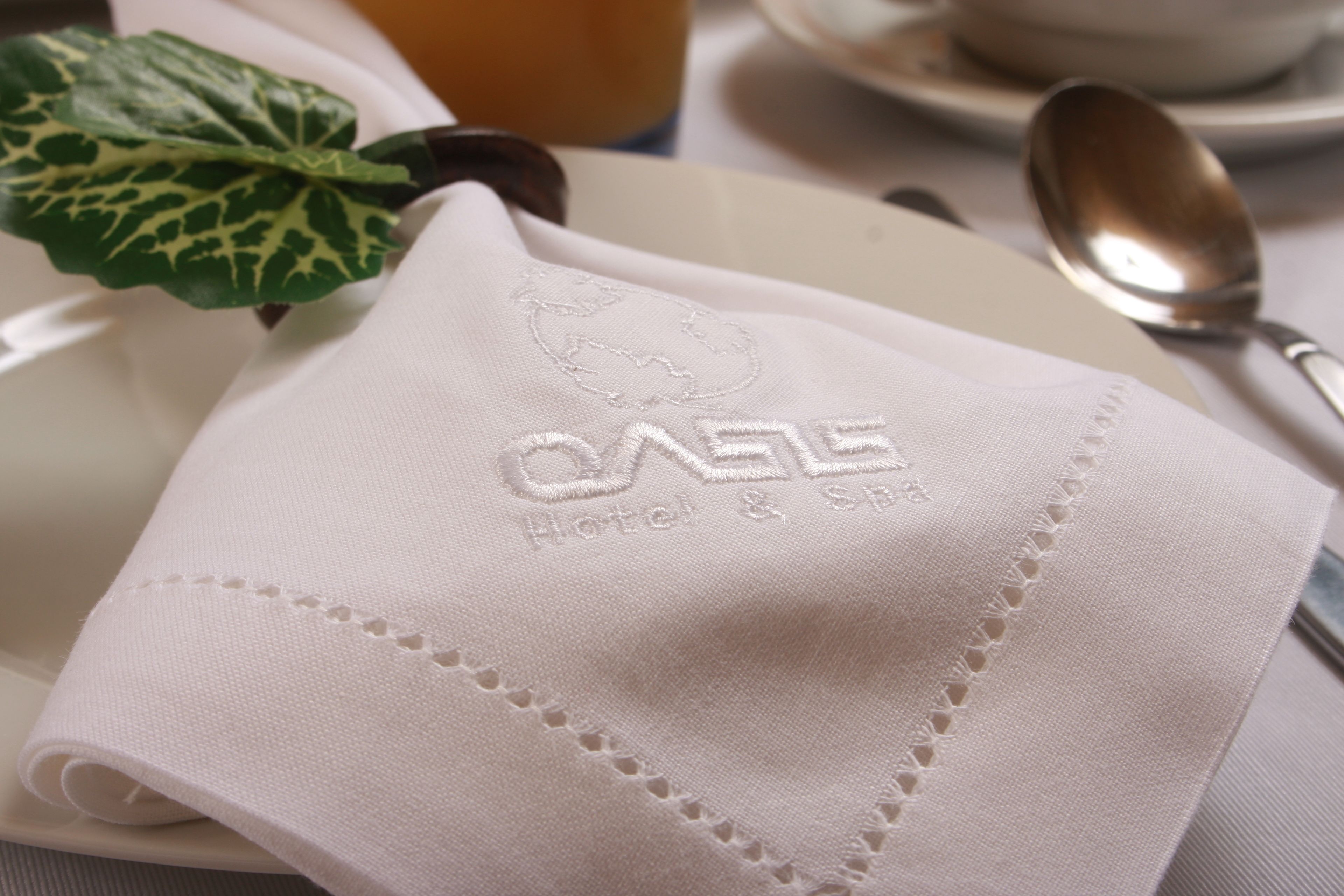A neatly folded white napkin with embroidered text on a white plate.