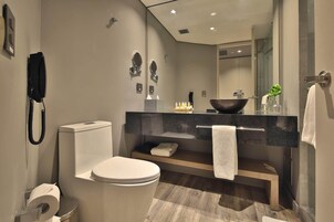Un baño moderno con inodoro, bidé, tocador con un espejo grande y lavamanos.