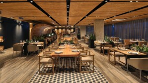 Un restaurante moderno con mesas largas compartidas, cabinas individuales y un piso con estampado de cuadros.