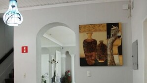 Ein geräumiger Flur mit Treppe links, einem Essbereich im Hintergrund und einem Gemälde an der Wand.