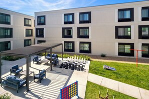 Un edificio moderno con un patio que cuenta con asientos al aire libre, un tablero de ajedrez y un tablero de juego a cuadros.