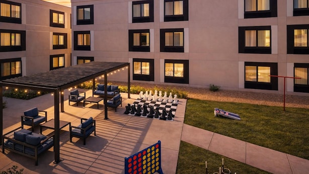 A modern building with multiple windows, outdoor seating, and a chessboard. - Hampton Inn & Suites by Hilton San Diego SeaWorld Near Old Town (San Diego)