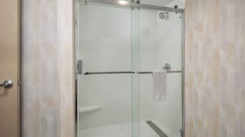 A glass-enclosed shower stall with a towel hanging on the door handle.