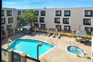 A hotel with a swimming pool, outdoor seating, and a palm tree. - Hampton Inn & Suites by Hilton San Diego SeaWorld Near Old Town (San Diego)