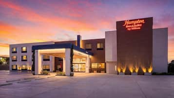 A Hampton Inn & Suites by Hilton building with a covered entrance and a prominent sign.